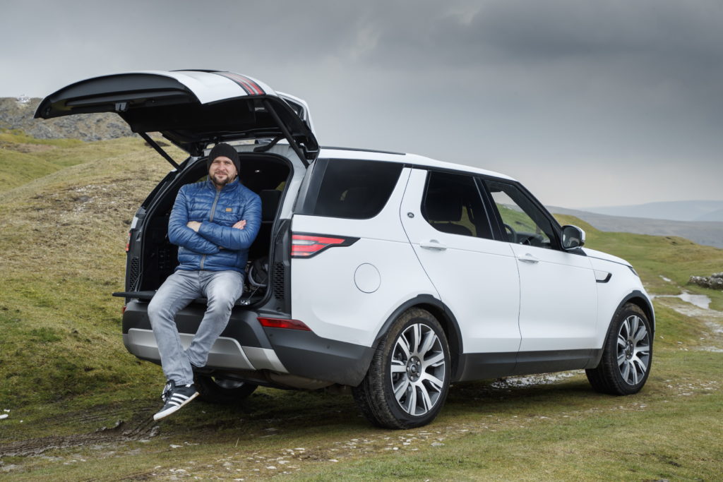 Tim leaning against the open boot of a Land Rover Discovery