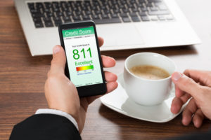 Man with up of tea looking at his credit score on his phone