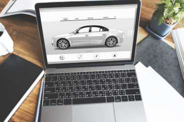 silver laptop on a desk with a silver car on the screen