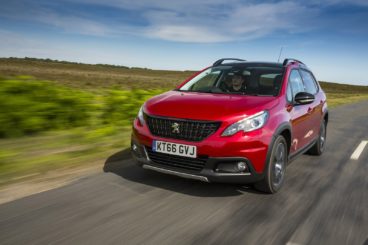Red Peugeot 2008 driving fast on a country road