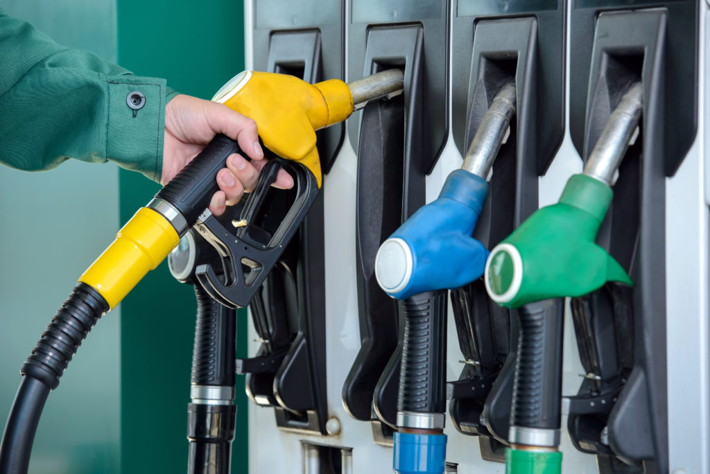 petrol pumps of different colours with a person in a green suit holding one of the pumps