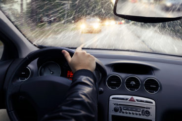 person in a leather jacket driving a car in heavy rain
