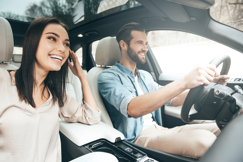 smiling couple with dark hair with man driving a car