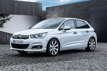 metallic white Citroen C4 on a cobbled driveway with a modern building in the background