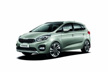 side view of a metallic kia carens diesel estate isolated on a white background
