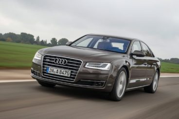 dark coloured Audi A8 saloon racing on the track with green trees in the background