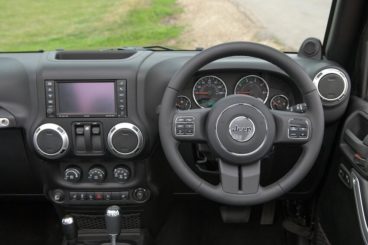 The black interior, steering wheel and infotainment system of the jeep wrangler hard top SUV