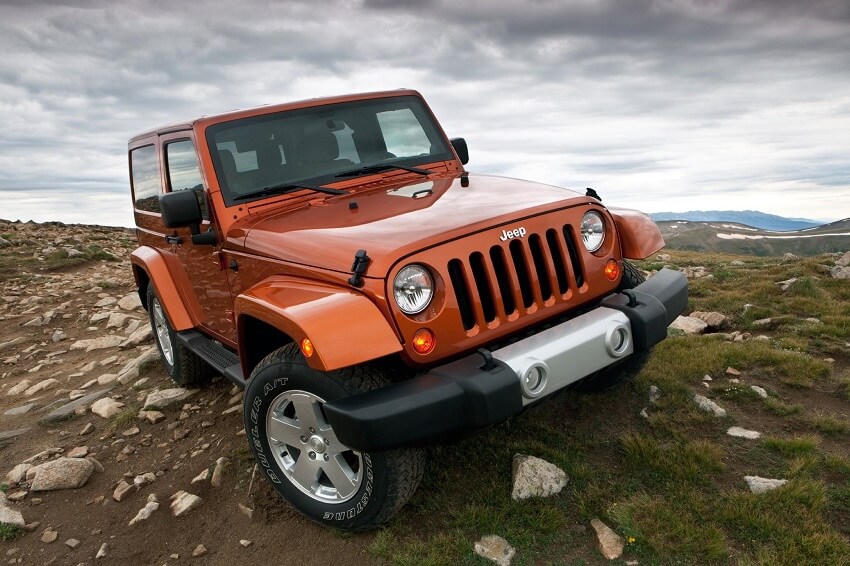 orange jeep wrangler hard top SUV driving some tough and rocky terrain