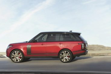 side view of a red Land Rover Range Rover SUV parked on road