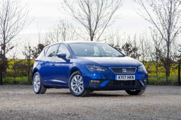 metallic blue coloured SEAT Leon parked on tarmac with bare trees in the background