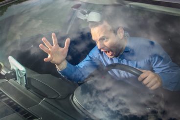 shot of man in blue shirt getting angry at his sat nav getting him lost
