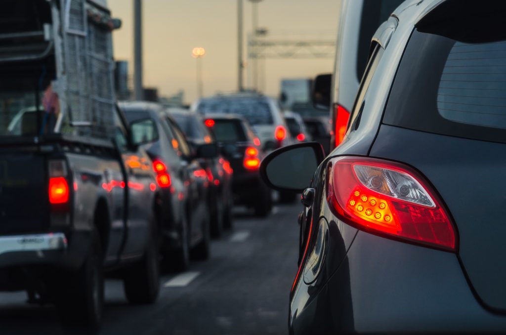Line of cars at dusk stuck in traffic with brake lights on