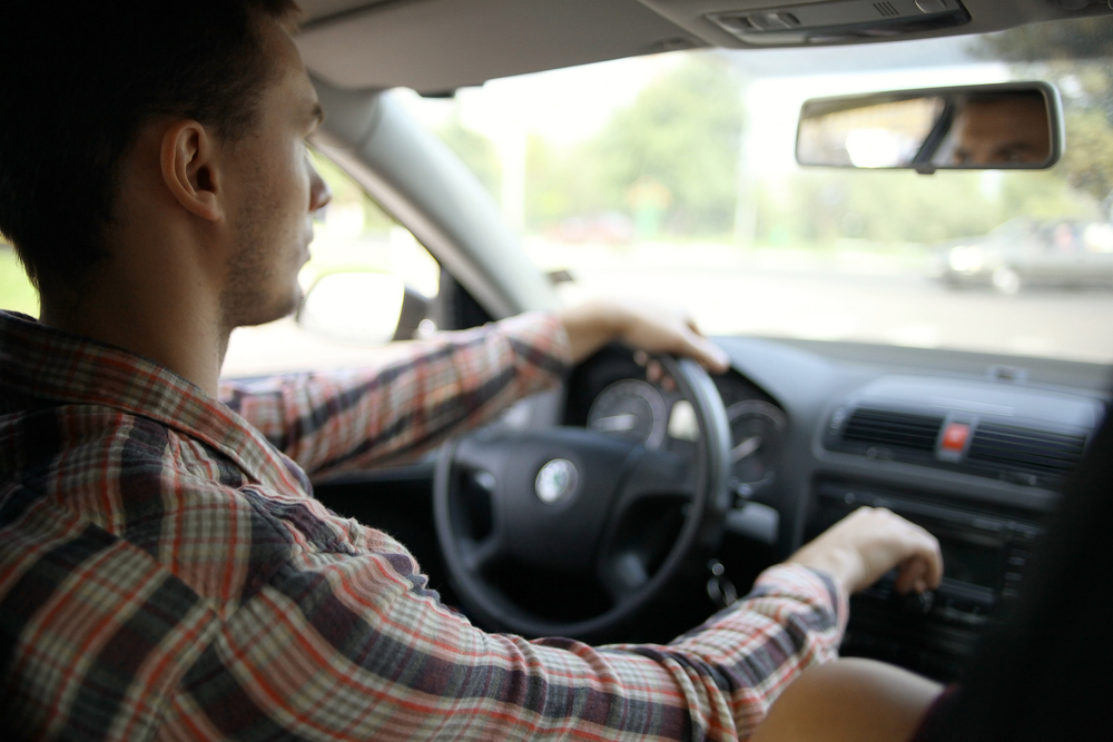 man with a checked shirt driving a car