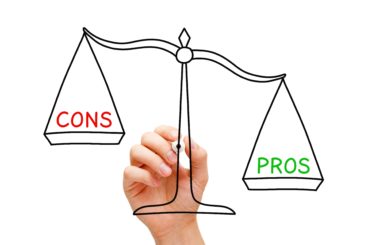 hand drawing uneven pros and cons scales on clear window with black pen