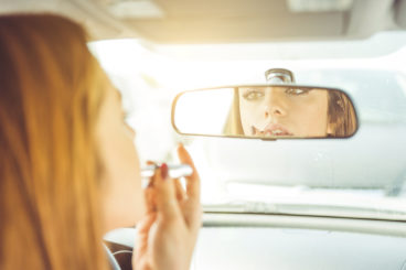 putting lipstick on in the rear view mirror - bizarre things