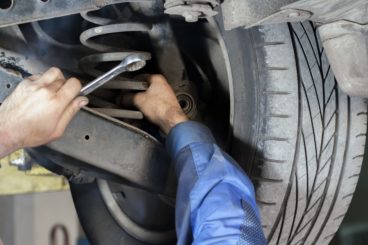 mechanic checking and fixing the suspension spring on a car