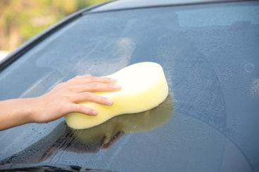 man washing car windscreen - driving in the dark