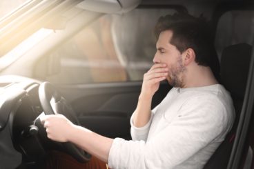 tired male driver yawning whilst driving