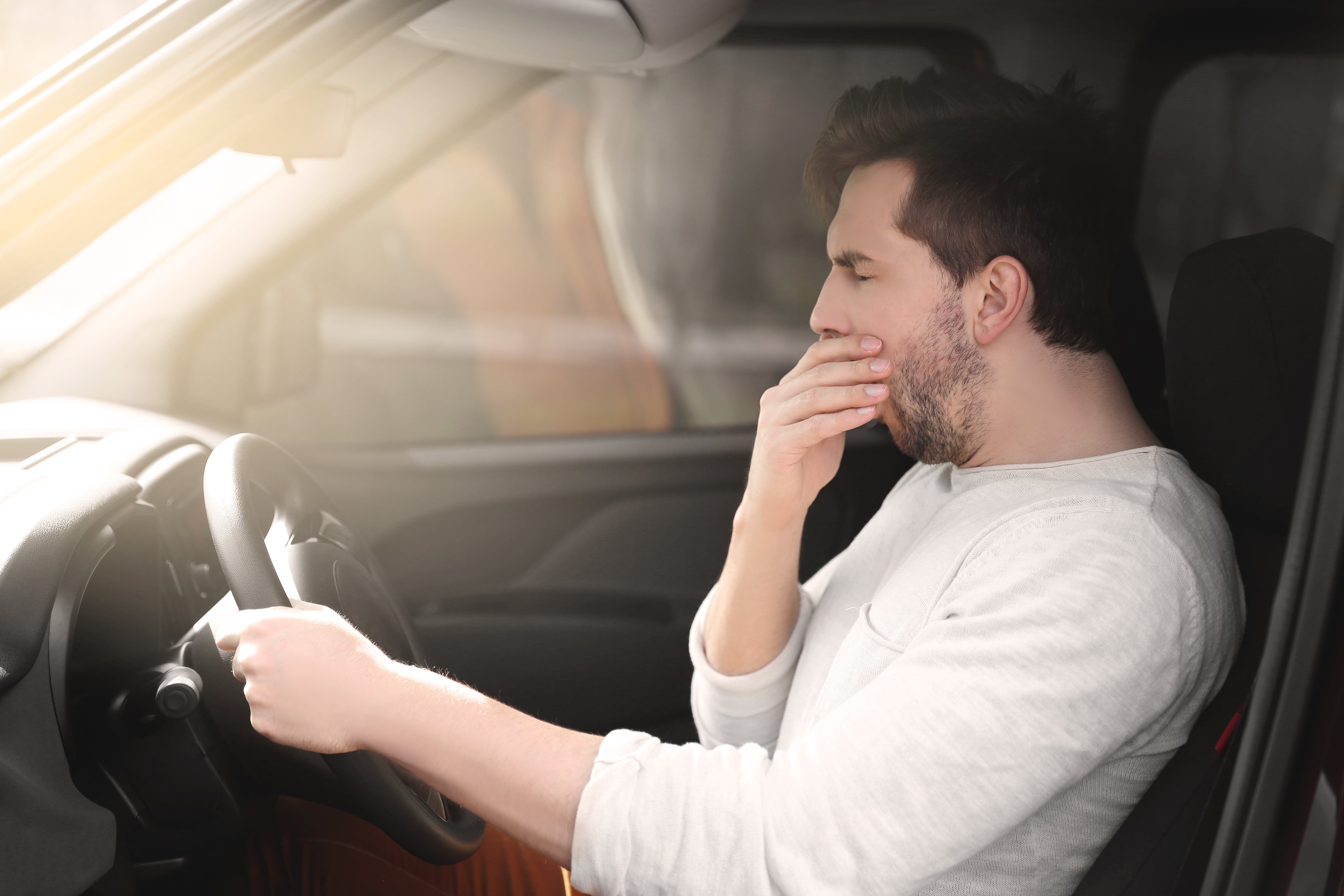 tired male driver yawning whilst driving