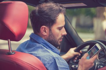 man distracted by his phone sitting in red leather
