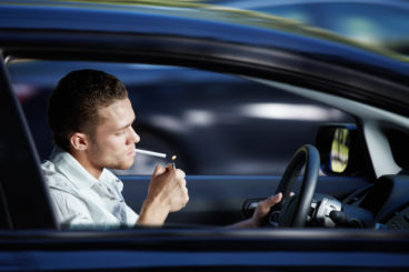 man lighting cigarette whilst driving - distractions when driving