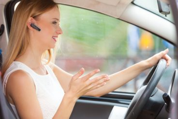blond women talking on the phone via Bluetooth headset whilst driving