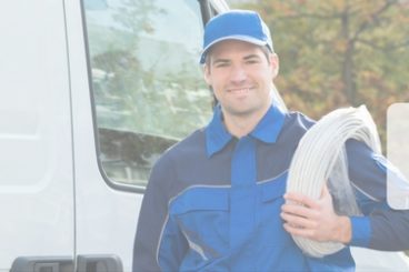 edited picture of electrician in a blue jump suit carrying roll of white cable standing next to his white van with the title best vans for electricians