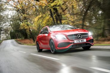 red mercedes benz a-class amg hatchback driving down wet road in forest area