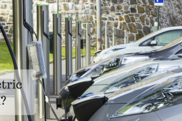 When were electric cars invented header image with electric cars charging in the background