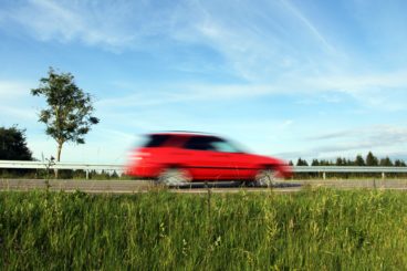 red car speeding through quite road