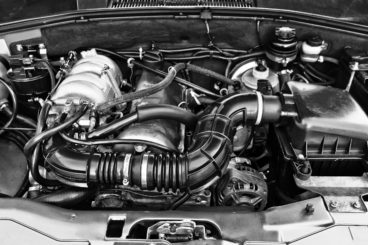 black and white photo of a cars hood open to show its engine