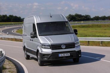 silver volkswagen crafter van driving down winding tarmac road