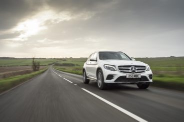 white mercedes-benz glc diesel estate driving down tarmac road with green fields on either side