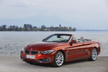 a brightly coloured BMW 4 Series Cabriolet parked on tarmac in front of the sea
