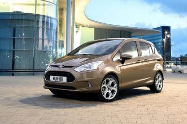 metallic ford bmax parked on tarmac in front of modern building and blue skys in the background