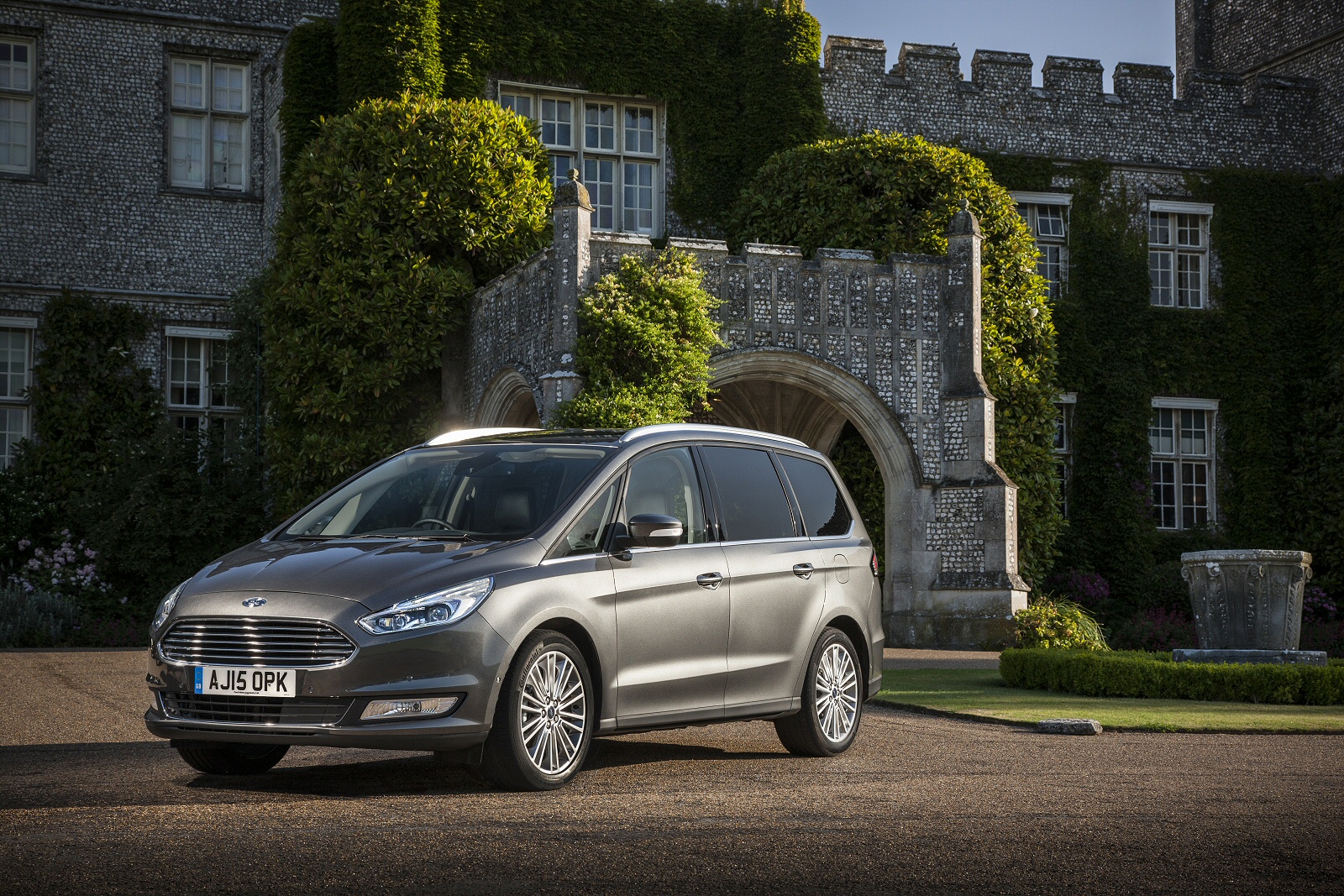 dark grey metallic ford galaxy parked on tarmac driveway in front of country house