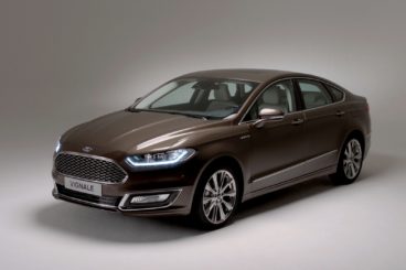 a metallic ford vignale diesel estate with headlights on isolated on a grey background