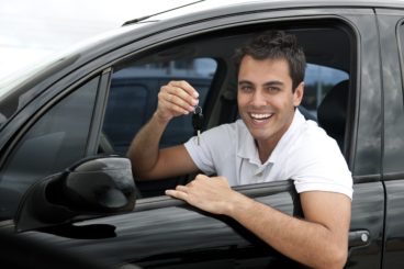 Happy Hispanic man showing the key of his new car