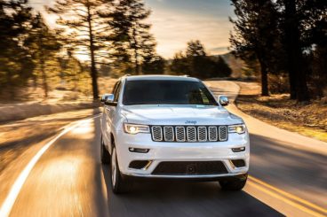 Jeep Grand Cherokee driving along a country road in the sunset