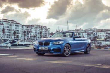 metallic blue bmw 2 series cabriolet parked near small habour town