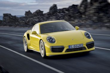 the yellow porsche 911 turbo driving on tarmac road with a blurred background