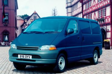 Blue Toyota Hiace parked in a town centre with buildings in the background