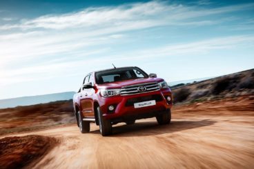 red toyota hilux pick up truck driving in orange desert setting