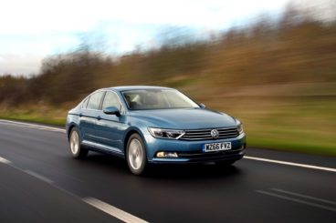 VW Passat driving on tarmac road with blurred trees in the background