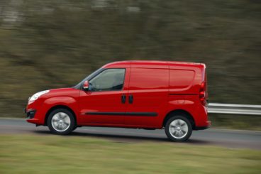 Red Vauxhall Combo driving at speed along a road with trees in the background