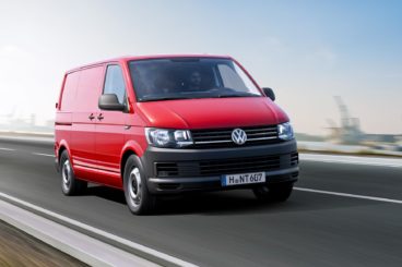 red Volkswagen transporter t6 van driving down tarmac road