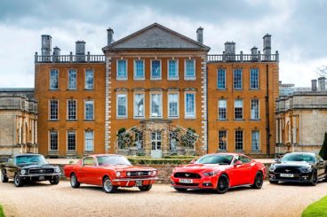 The first ford mustangs parked alongside the new ford mustangs all parked on gravel driveway in front of mansion