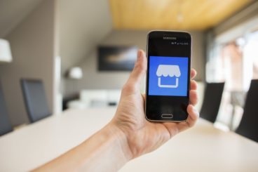 Image of man holding phone displaying Facebook marketplace