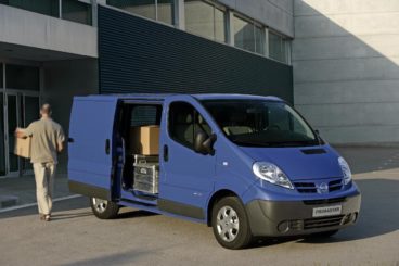 blue nissan primastar parked infront of modern building being unpacked by delivery driver