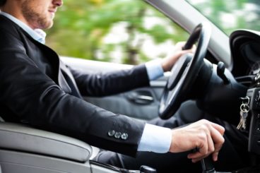 business man with a beard in a suit driving his company lease car